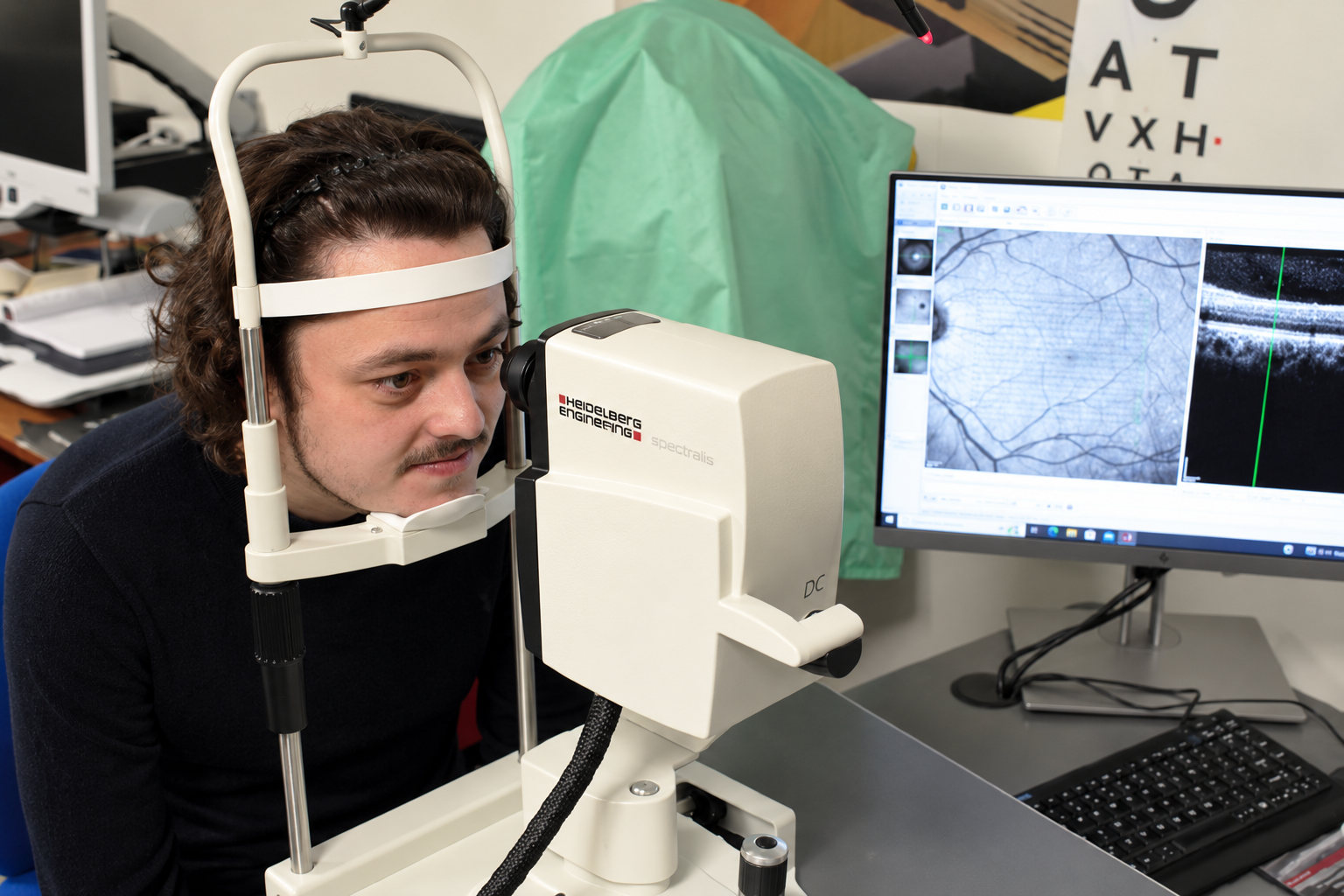 A man resting his chin at a retinal imaging machine during an eye scan.